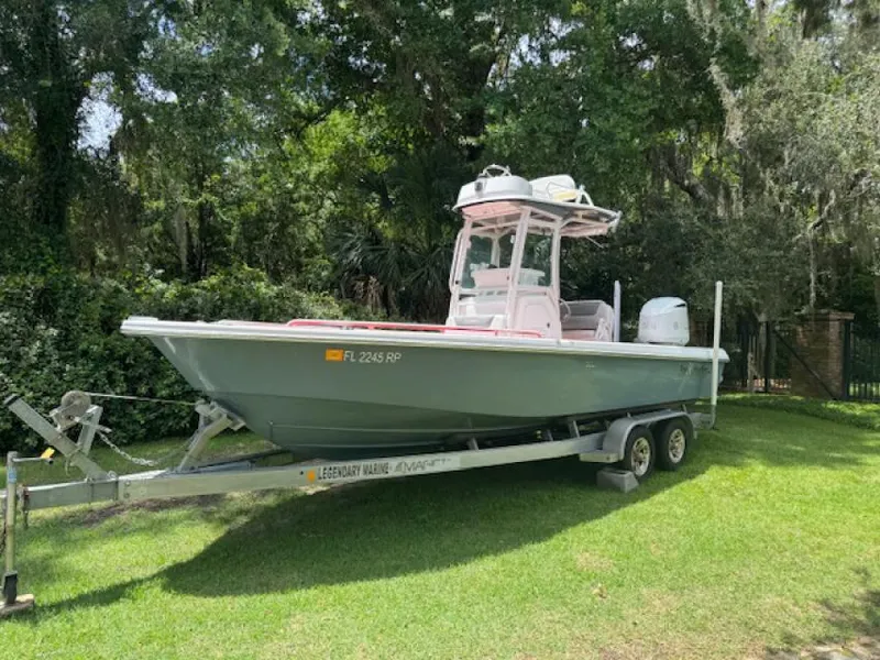 Slide: The Image of 2018 Everglades 243CC boat on trailer, parked on grass, surrounded by trees. - 2