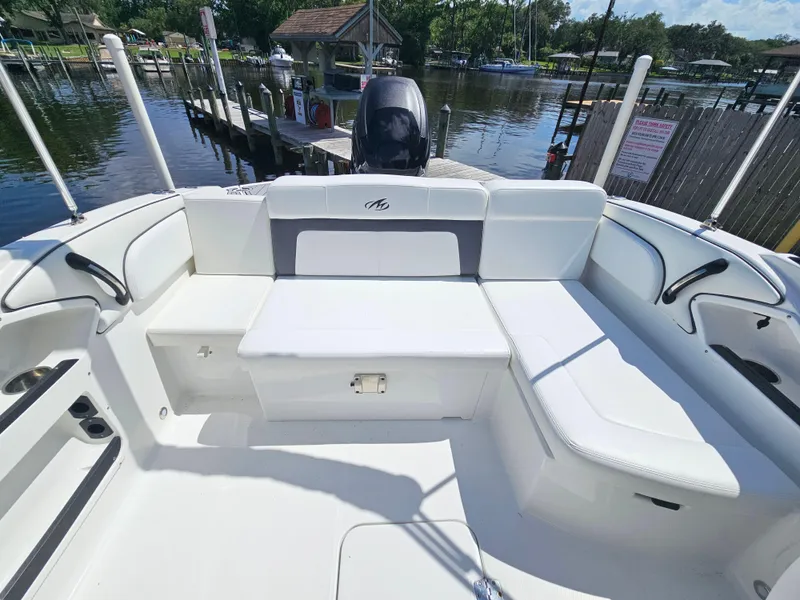 Slide: The Image of 2017 Monterey 217 Outboard boat interior with white seating, docked by a scenic waterfront. - 11