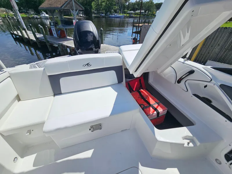 Slide: The Image of 2017 Monterey 217 Outboard boat interior with open storage compartment and dock view. - 13