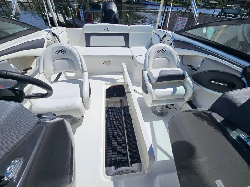 Slide: The Image of 2017 Monterey 217 Outboard boat interior with seating and steering wheel, docked by the water. - 17