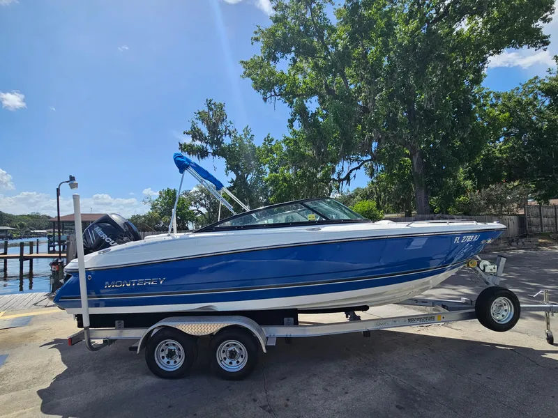 Slide: The Image of 2017 Monterey 217 Outboard boat on trailer, blue and white, parked near water. - 3