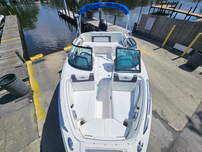Slide: The Image of 2017 Monterey 217 Outboard boat docked, featuring open seating and a blue canopy. - 31