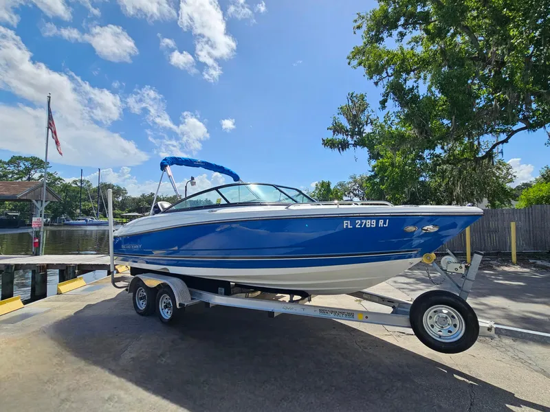 Slide: The Image of 2017 Monterey 217 Outboard boat on trailer, blue and white, parked near a dock. - 4