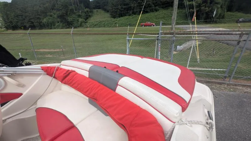 Slide: The Image of 2006 Sea Ray 185 Sport boat with red and white seating, parked near a fence. - 5