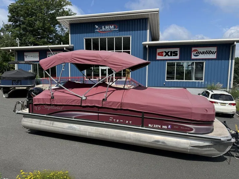 Slide: The Image of 2015 Premier 250 Solaris pontoon boat with maroon cover at a marine dealership. - 22
