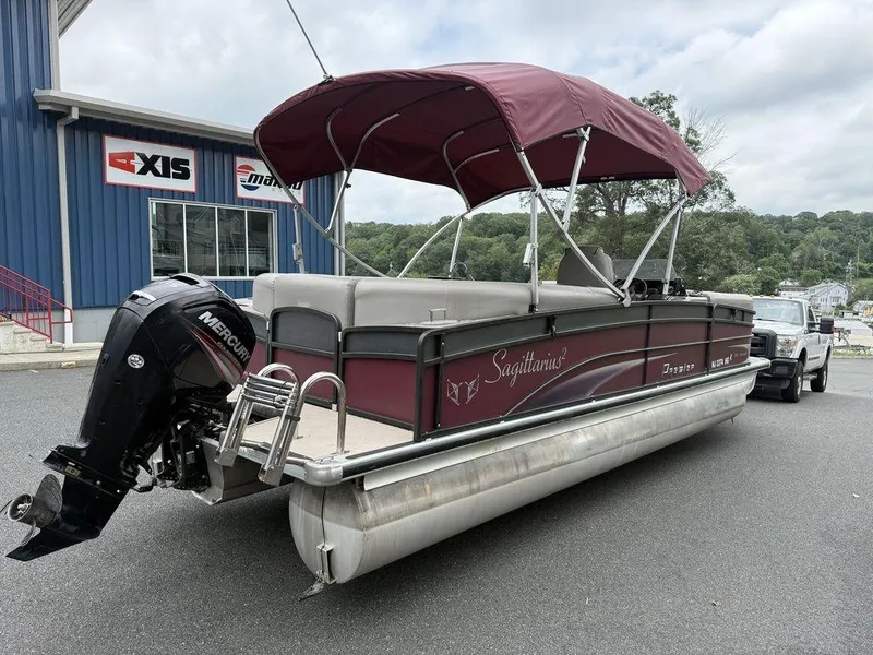 Slide: The Image of 2015 Premier 250 Solaris pontoon boat with Mercury engine, parked near a dealership. - 5
