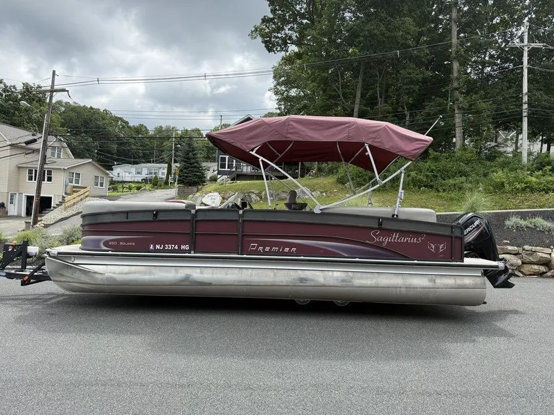 Slide: The Image of 2015 Premier 250 Solaris pontoon boat with maroon canopy parked on a residential street. - 6