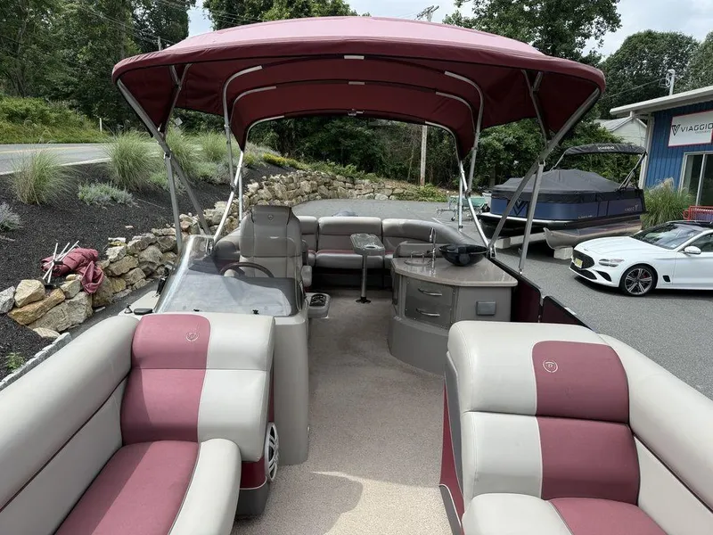 Slide: The Image of 2015 Premier 250 Solaris pontoon boat with maroon canopy and seating, parked outdoors. - 8