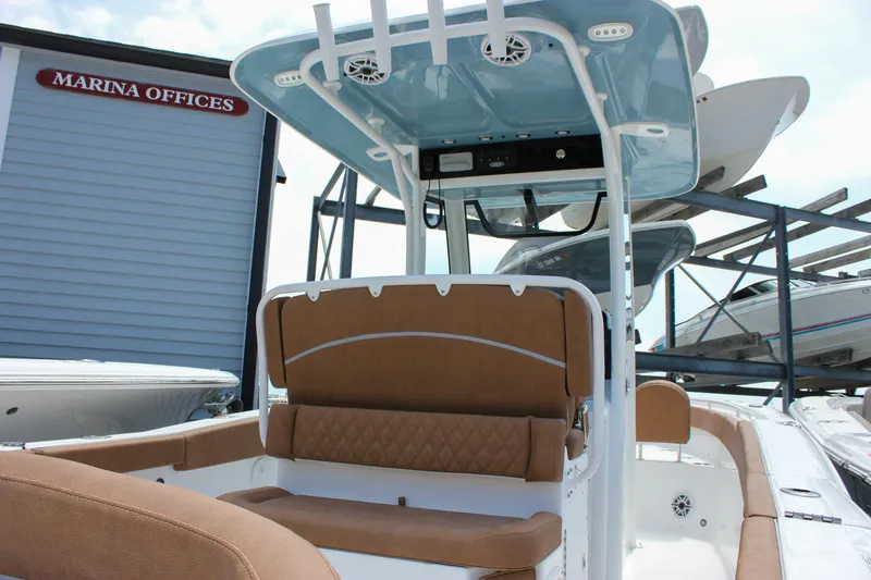 Slide: The Image of 2026 Sea Hunt Ultra 265 SE boat interior at marina with brown seating and blue canopy. - 17