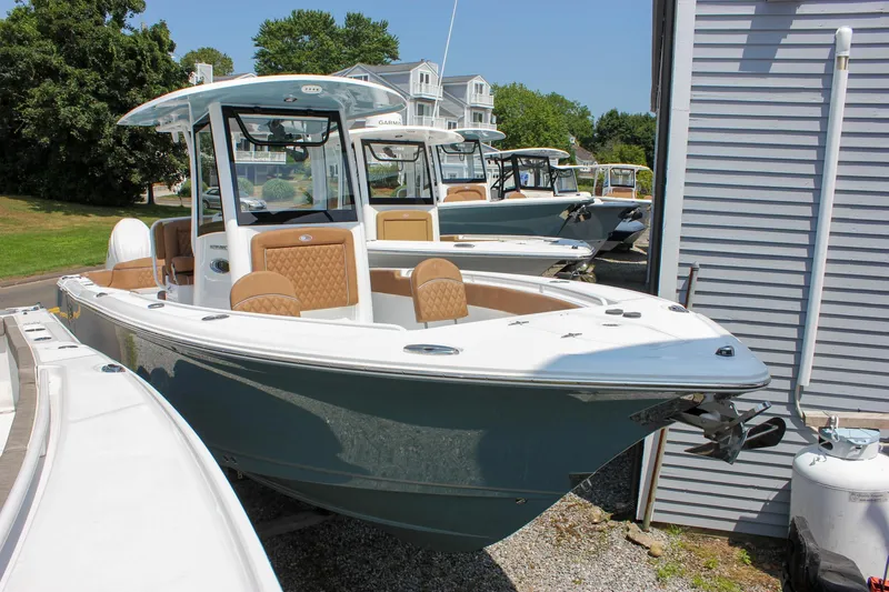 Slide: The Image of 2026 Sea Hunt Ultra 265 SE boat displayed outdoors near other boats. - 2