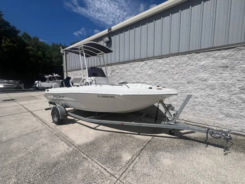Slide: The Image of 2021 Key Largo 1801 CC boat on trailer, parked outdoors near a building. - 2