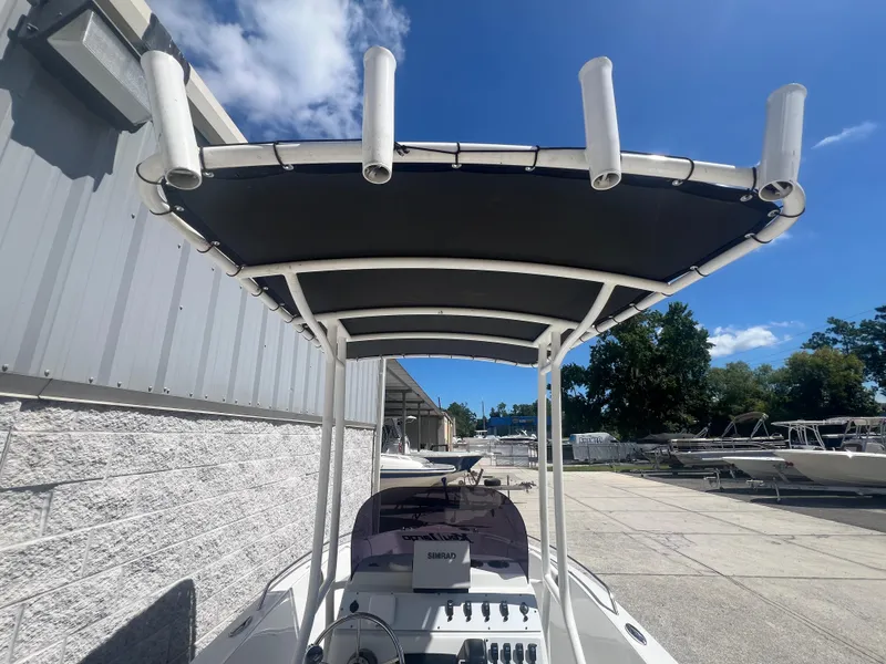 Slide: The Image of 2021 Key Largo 1801 CC boat with T-top and rod holders, parked outdoors. - 7