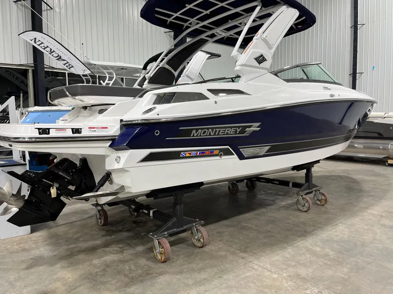 Slide: The Image of 2023 Monterey 298 Super Sport boat in showroom, side view, on wheeled supports. - 2