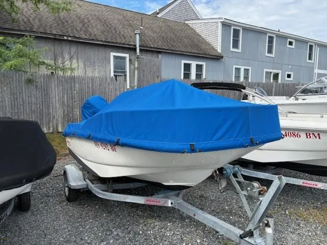Slide: The Image of 2016 Boston Whaler 130 SS boat with blue cover on trailer, parked outdoors. - 3