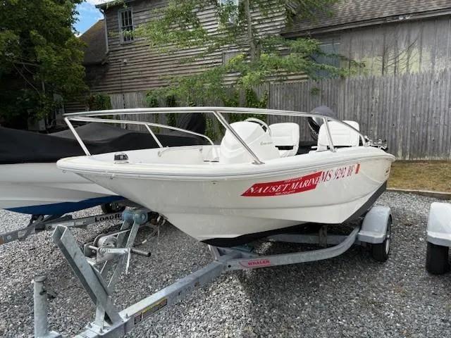 Slide: The Image of 2016 Boston Whaler 130 SS boat on trailer, parked outdoors near wooden fence. - 7