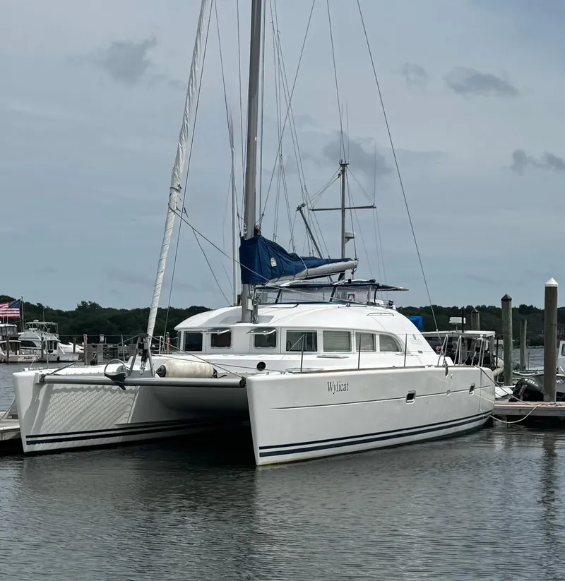 The Image of Lagoon 380 catamaran from 2000 docked at a marina, featuring white hull and blue sail. - 0