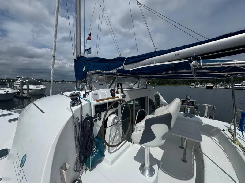 Slide: The Image of Lagoon 380 catamaran cockpit with steering wheel, seating, and marina view, 2000 model. - 12