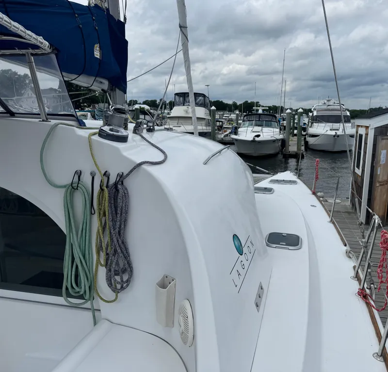 Slide: The Image of Lagoon 380 catamaran docked at marina, showcasing ropes and logo, under cloudy skies. - 5