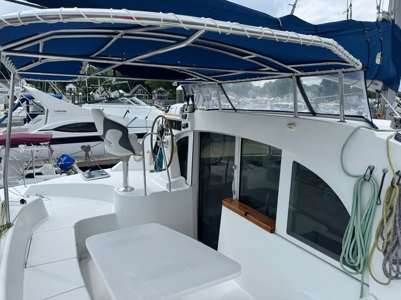 Slide: The Image of Lagoon 380 catamaran cockpit with blue canopy, steering wheel, and ropes, docked at marina. - 6