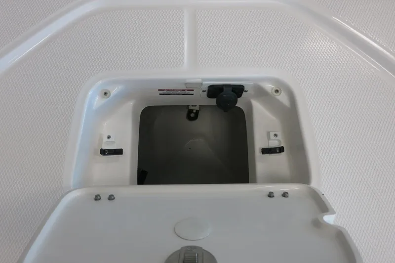 Slide: The Image of 2025 Robalo 226 Cayman boat storage compartment, open lid, white interior. - 12