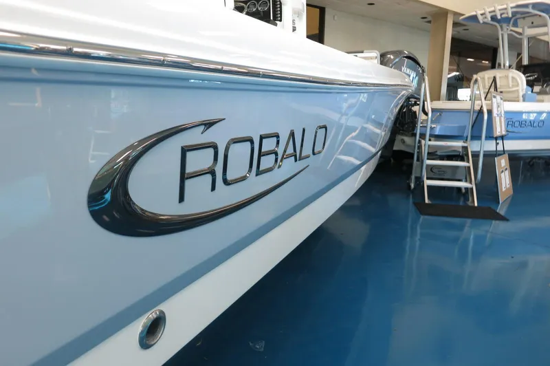 Slide: The Image of 2025 Robalo 226 Cayman boat displayed in showroom, side view with logo. - 3
