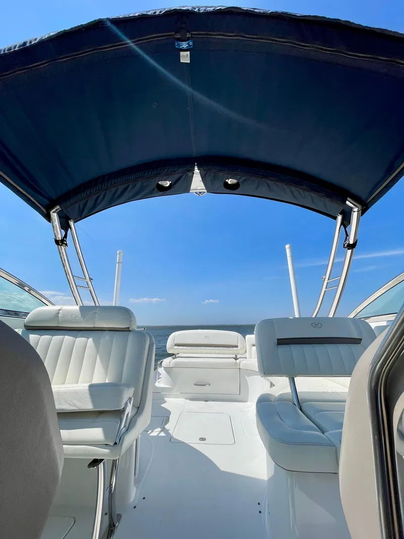 Slide: The Image of 2006 Cobalt 323 boat interior with blue canopy and white seating, under clear blue sky. - 18