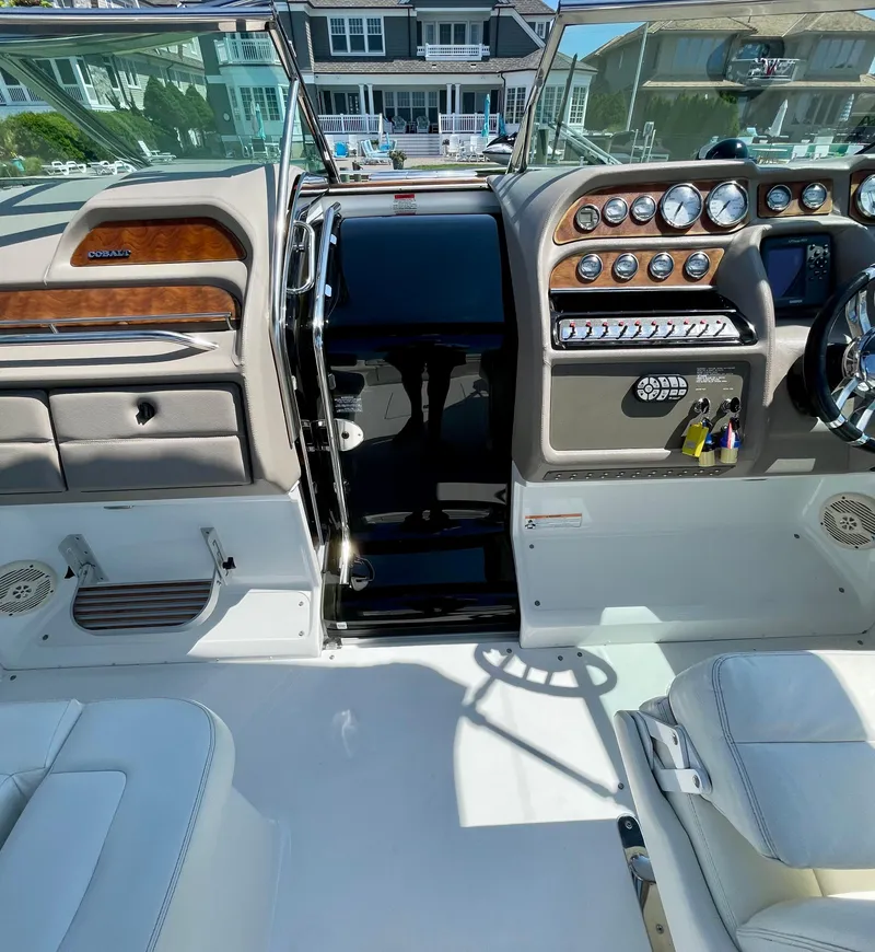 Slide: The Image of 2006 Cobalt 323 boat interior with dashboard and controls, docked near waterfront homes. - 20