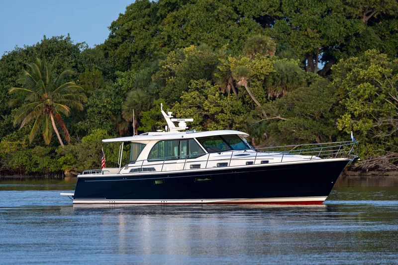Slide: The Image of 2026 Sabre 51 Salon Express yacht cruising near lush tropical shoreline. - 19
