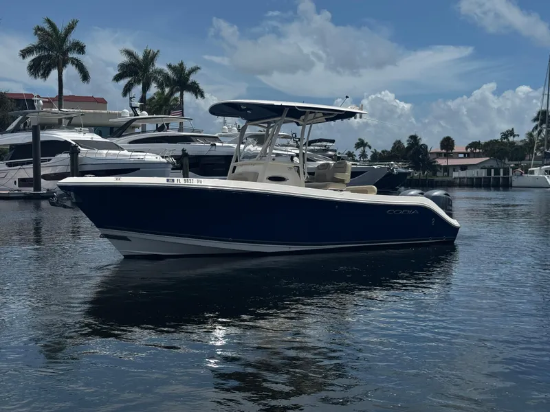 Slide: The Image of 2015 Cobia 237 Center Console boat docked in a marina with palm trees. - 0