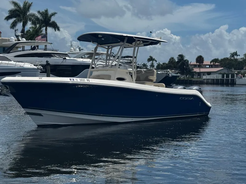 Slide: The Image of 2015 Cobia 237 Center Console boat on calm water, surrounded by yachts and palm trees. - 1