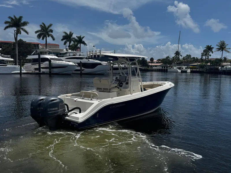 Slide: The Image of 2015 Cobia 237 Center Console boat on water, with Yamaha engines, docked near palm trees. - 10