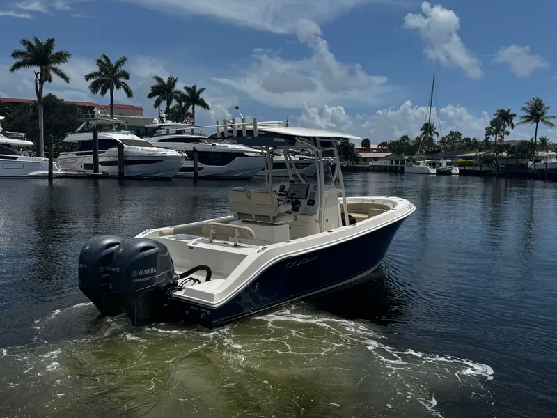Slide: The Image of 2015 Cobia 237 Center Console boat with twin Yamaha engines docked in marina. - 11