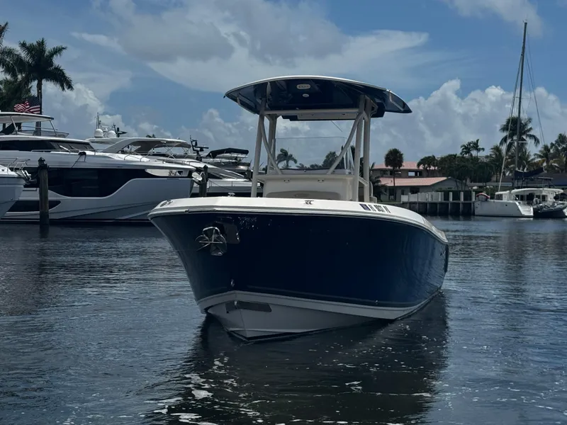 Slide: The Image of 2015 Cobia 237 Center Console boat on calm water, surrounded by yachts. - 2