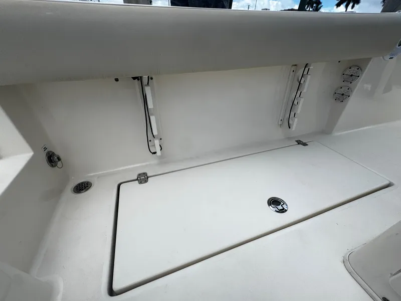 Slide: The Image of 2015 Cobia 237 Center Console boat interior, featuring storage compartment and clean white finish. - 23