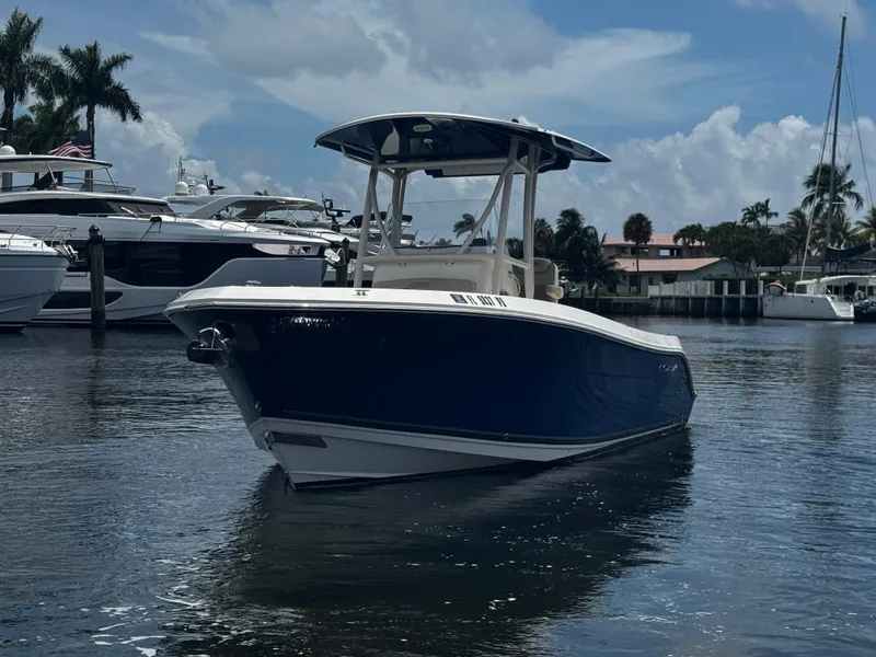 Slide: The Image of 2015 Cobia 237 Center Console boat on calm water, surrounded by yachts and palm trees. - 3