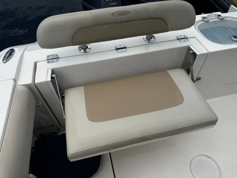 Slide: The Image of 2015 Cobia 237 Center Console boat with beige foldable seat and storage compartment. - 32