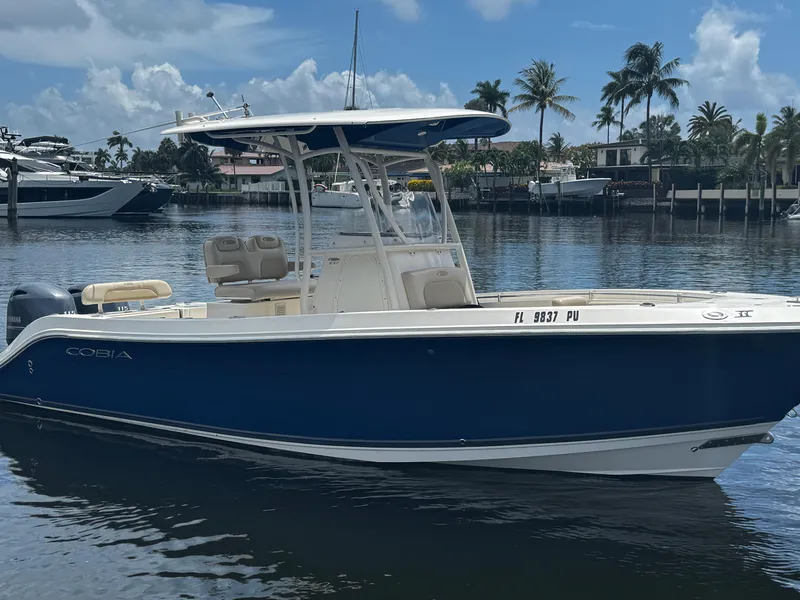 Slide: The Image of 2015 Cobia 237 Center Console boat on calm water, with palm trees in the background. - 5