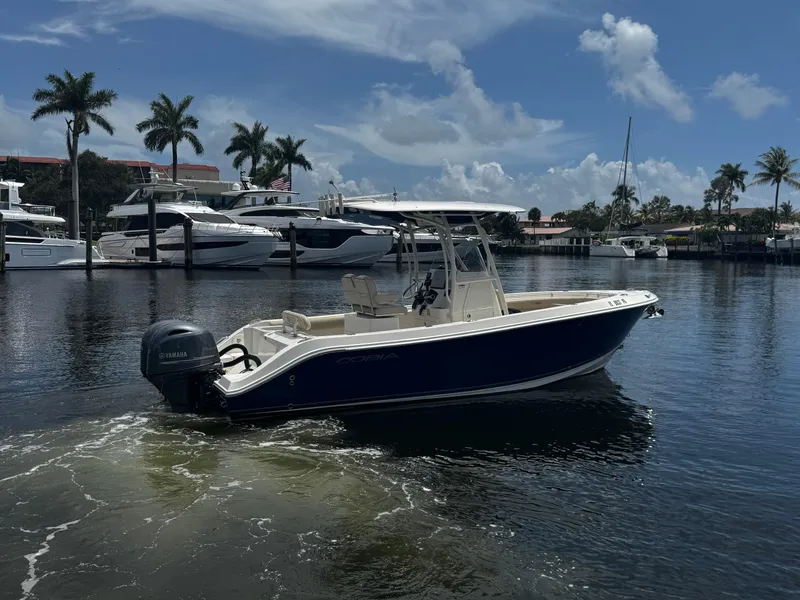 Slide: The Image of 2015 Cobia 237 Center Console boat on calm water with palm trees in the background. - 8
