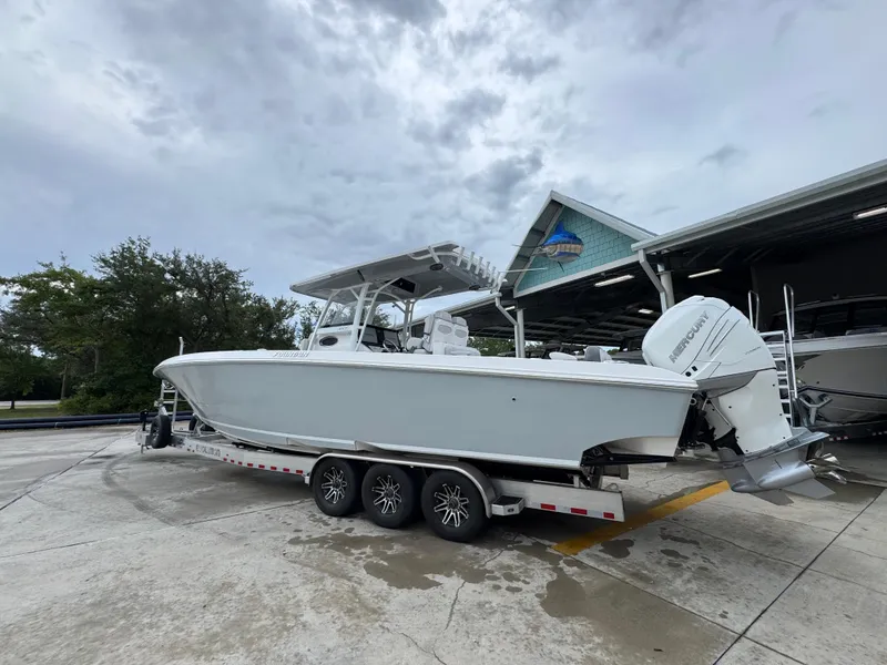 Slide: The Image of 2022 Fountain 38 CC boat on trailer, parked outdoors under cloudy sky. - 17
