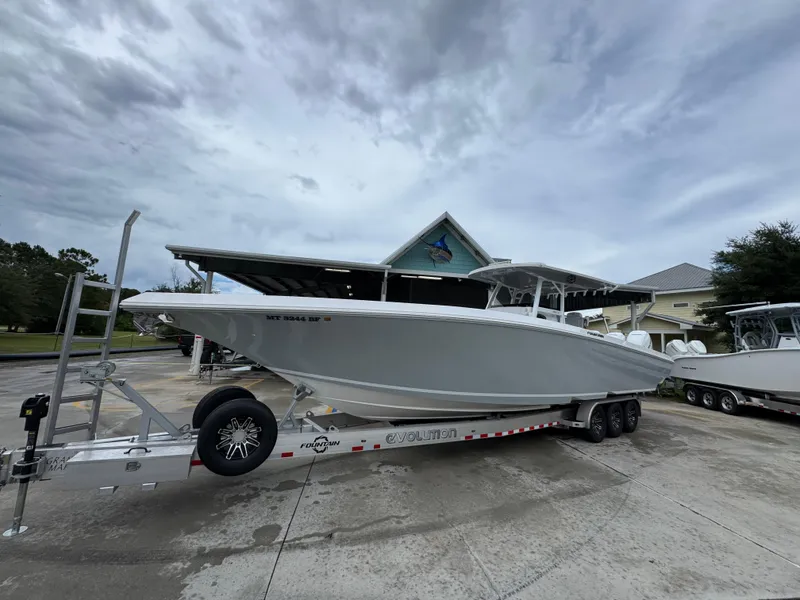 Slide: The Image of 2022 Fountain 38 CC boat on trailer, parked outdoors under cloudy sky. - 3