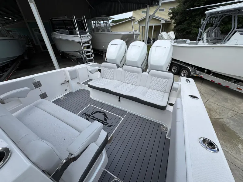 Slide: The Image of 2022 Fountain 38 CC boat interior with seating and outboard motors in a marina setting. - 37