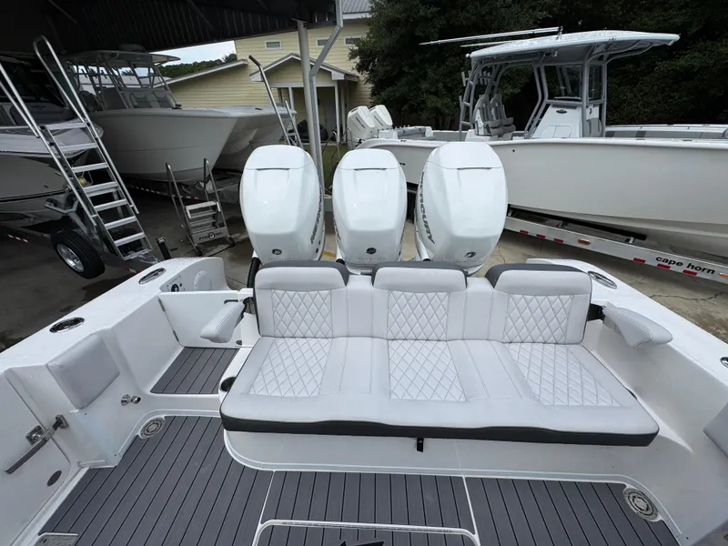 Slide: The Image of 2022 Fountain 38 CC boat with triple outboard engines and cushioned seating. - 38