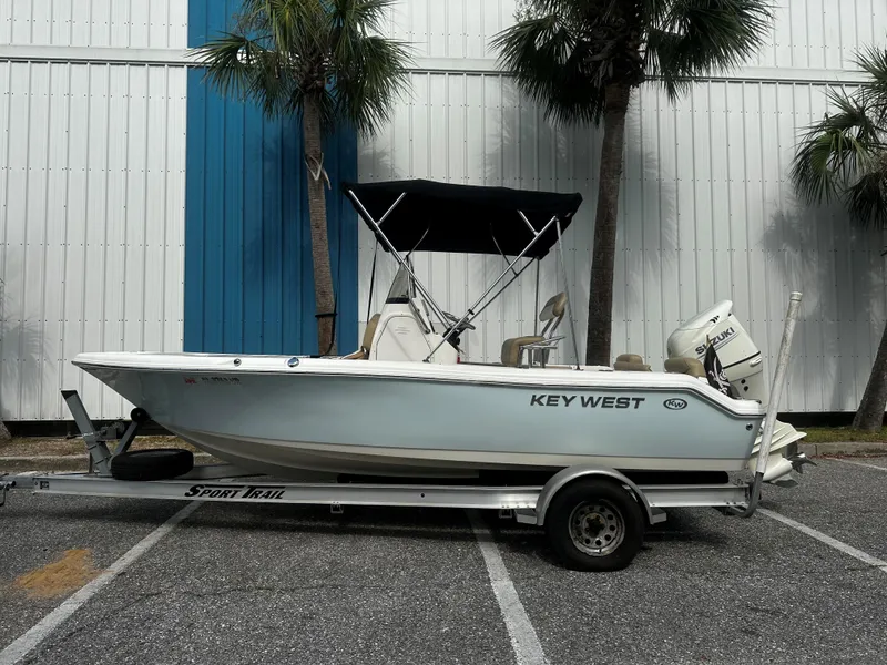 The Image of 2019 Key West 189FS boat on trailer, parked outdoors near palm trees. - 1