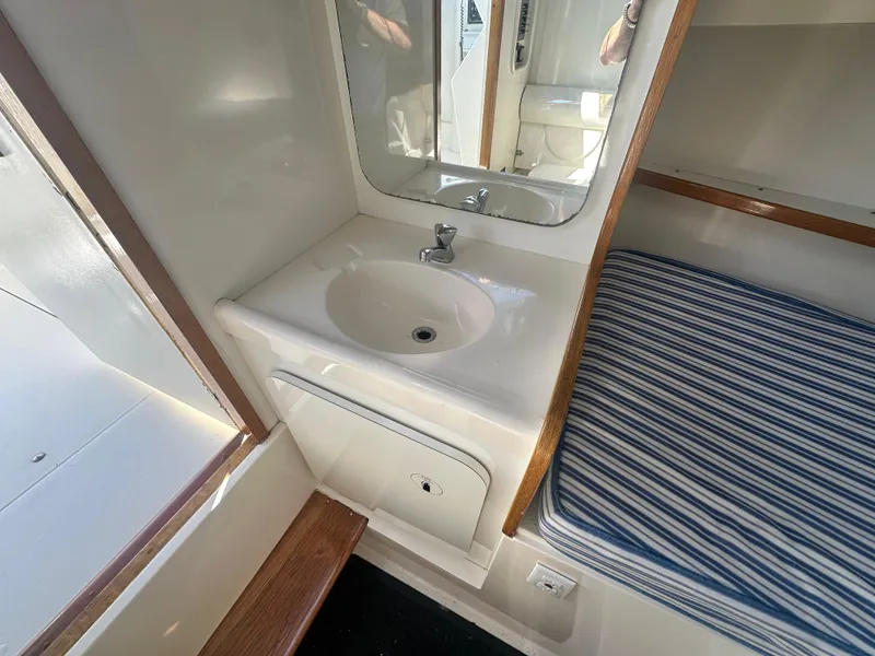 Slide: The Image of Interior of 1988 Bertram 28 Moppie with sink and striped bedding. - 10