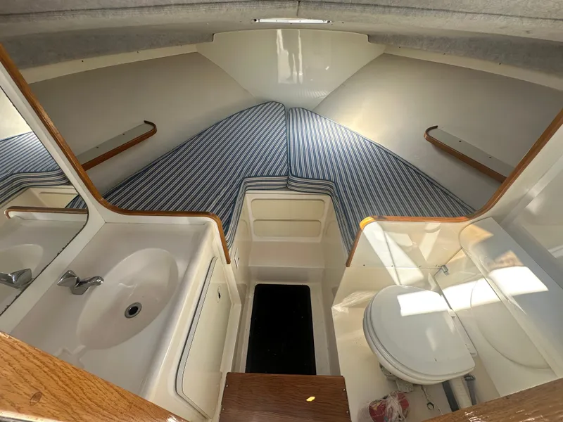 Slide: The Image of Interior of 1988 Bertram 28 Moppie boat with striped bedding and compact bathroom. - 11