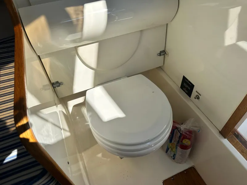 Slide: The Image of 1988 Bertram 28 Moppie boat bathroom with white toilet and storage area. - 9