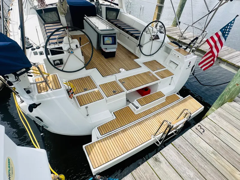Slide: The Image of 2015 Beneteau Oceanis 45 sailboat with dual steering wheels, docked with American flag. - 23