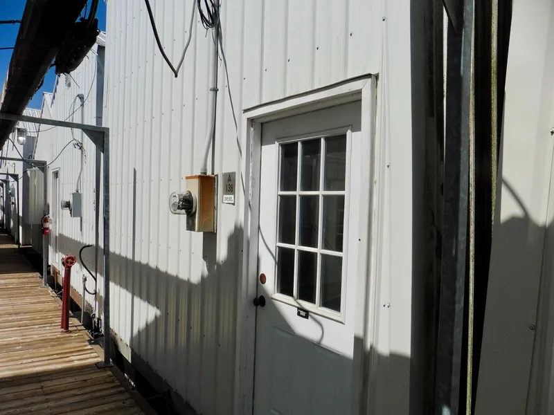 Slide: The Image of White boathouse with wooden walkway, labeled "A138," featuring a glass-paneled door. - 3