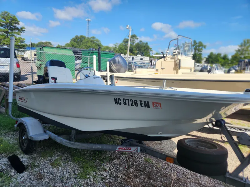 Slide: The Image of 2011 Boston Whaler 130 Super Sport boat on trailer, parked outdoors. - 0