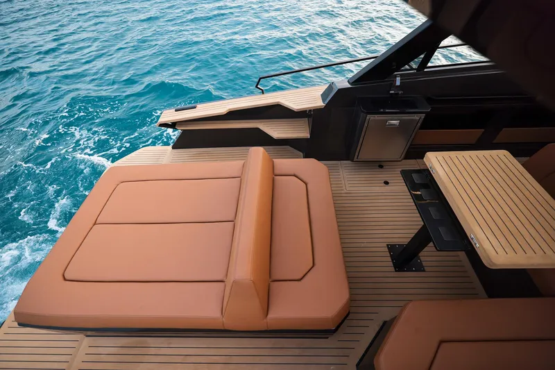 Slide: The Image of Luxurious Focus 3X 2025 yacht deck with tan seating and wooden table on blue ocean. - 16